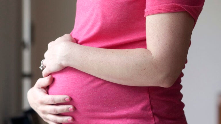 A pregnant woman stands for a portrait in Dallas.