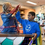 A boy high fives a Captain Marvel cosplayer.