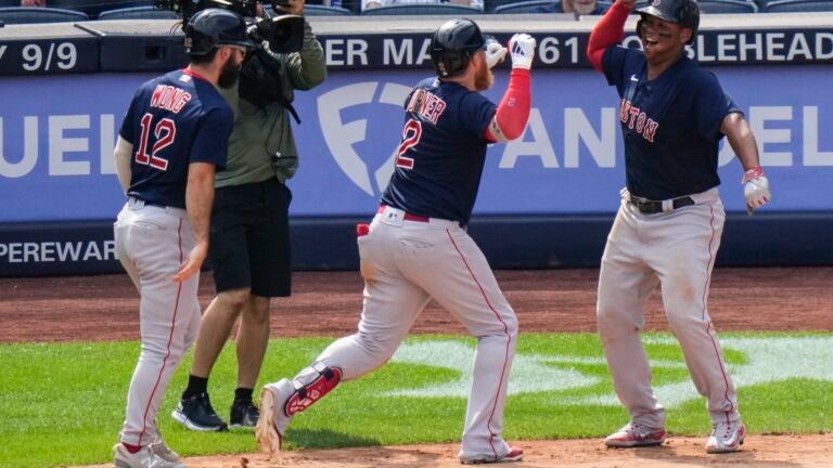Justin Turner of the Red Sox celebrates with Rafael Devers and Connor Wong after hitting a three-run home run during the seventh inning.