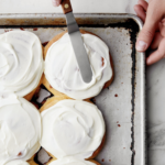 A tray of cookies being frosted.