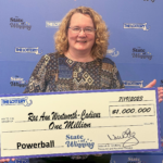 A smiling woman holds a large novelty check made out for $1 million.