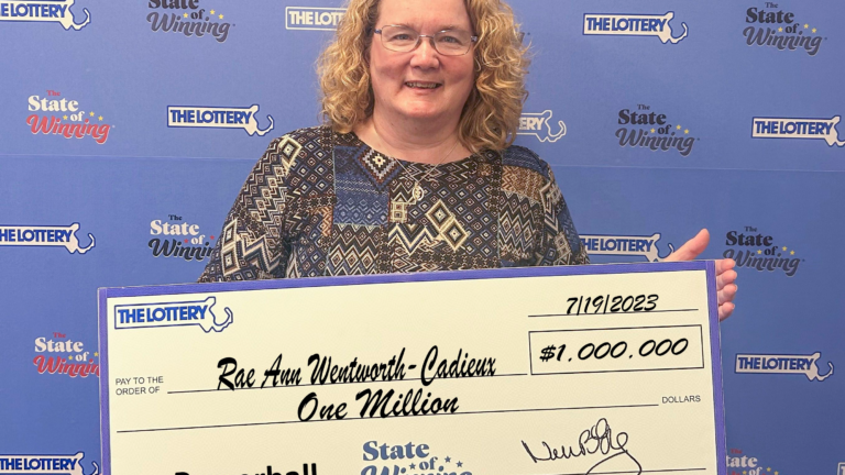 A smiling woman holds a large novelty check made out for $1 million.