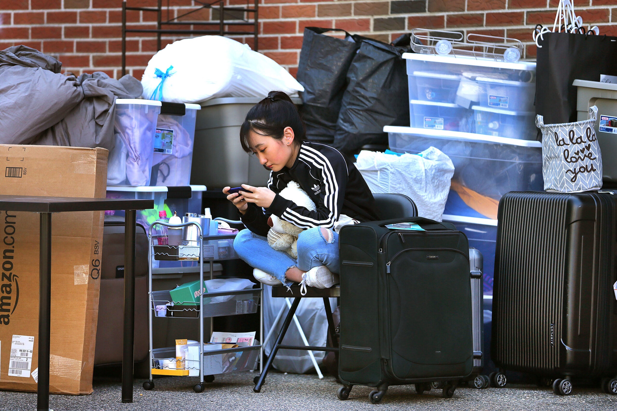 Boston University senior Yifei Ren sits amidst a pile of belongings of her friends and hers as she waited three hours on Saturday, Sept. 1, 2018 to get inside their apartment on Linden Street in Allston.