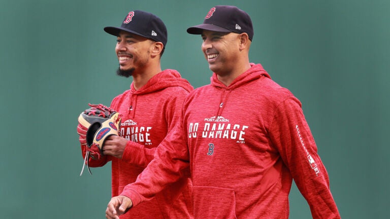 Red Sox RF Mookie Betts (left) and manager Alex Cora (right) are sporting "Do Damage" post season sweatshirts as they share a laugh while walking in the outfield.