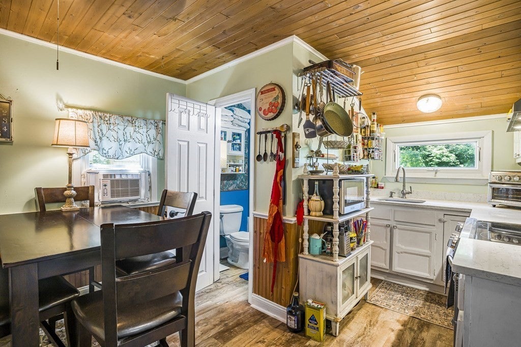 A kitchen in a Norton home with a hardwood floor, a wood paneled ceiling and white cabinets. 
