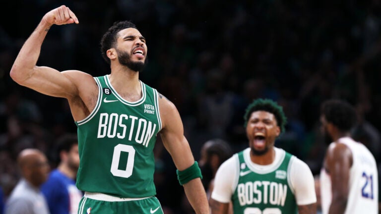 Celtics' Jayson Tatum (0) reacts after firing a three-pointer in the third quarter that puts Boston 73-58 ahead.  Teammate Marcus Smart (36) also reacted in the second half of the season when Joel Embiid (21) of the 76ers headed for the guest bench on the far right when Philadelphia took a time-out after the basket.  The Boston Celtics hosted the Philadelphia 76ers for game seven of their NBA Eastern Conference basketball semifinals series at TD Garden.