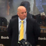 Bruins coach Jim Montgomery stands at the bench as Florida players celebrate on the ice after they beat the Bruins ion overtime.