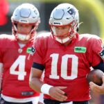 The Patriots held training camp on their practice field at Gillette Stadium. QB’s Bailey Zappe(left) and Mac Jones take a breather between passing drills.