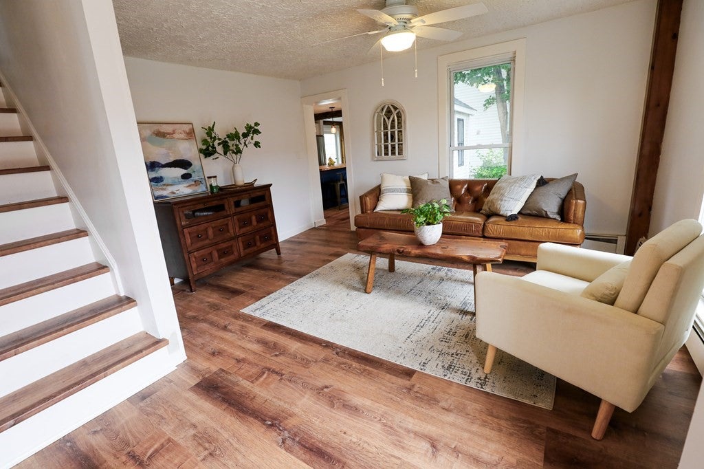 Living room in the Shirley house with a hardwood floor and white walls. 