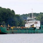 Spectators watch as a dredger works to deepen a shallow channel in the Kennebec River in Maine.