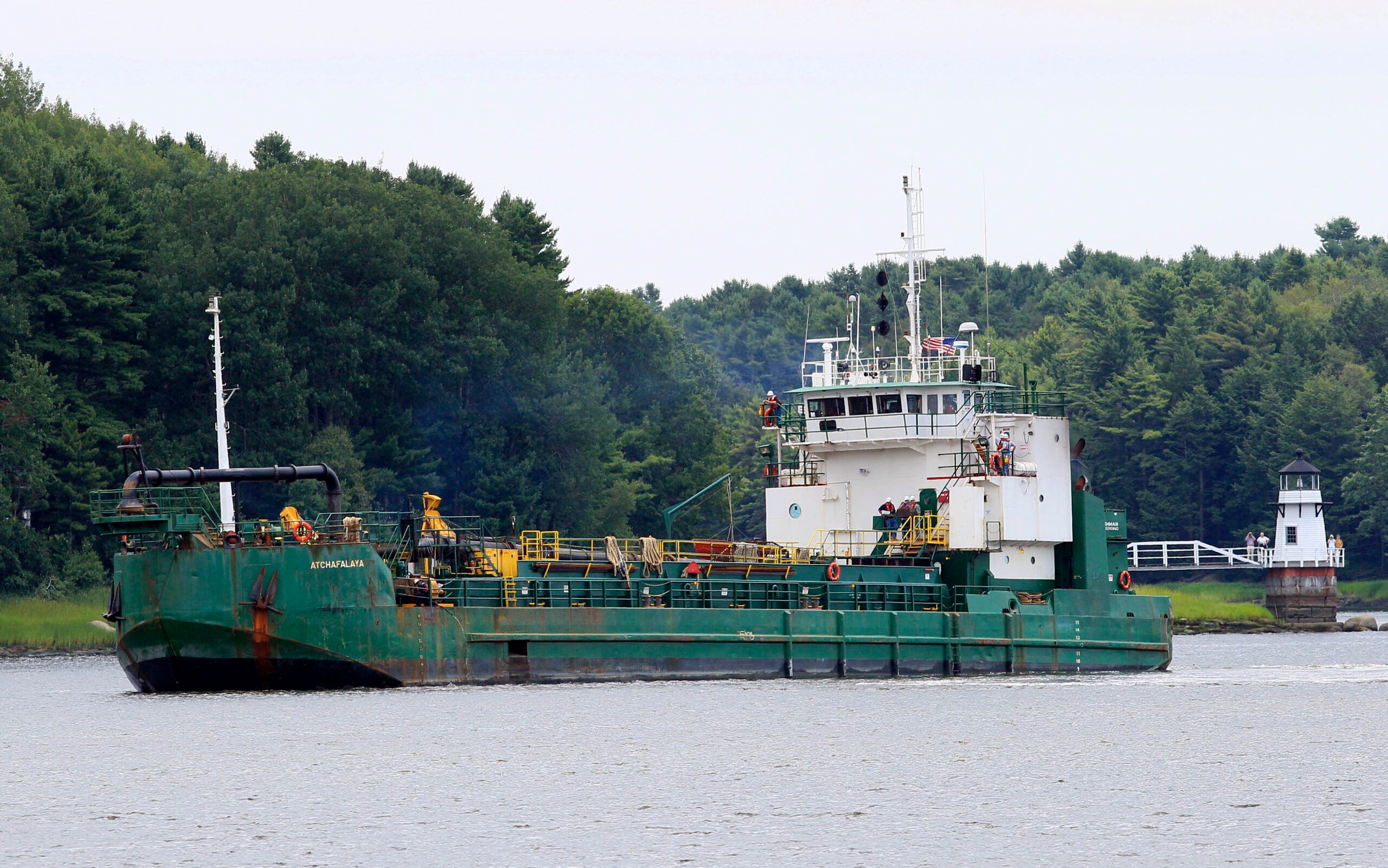 Spectators watch as a dredger works to deepen a shallow channel in the Kennebec River in Maine.