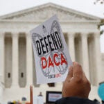 Someone holds up a "Defend DACA" sign during a rally in front of the Supreme Court in Washington.