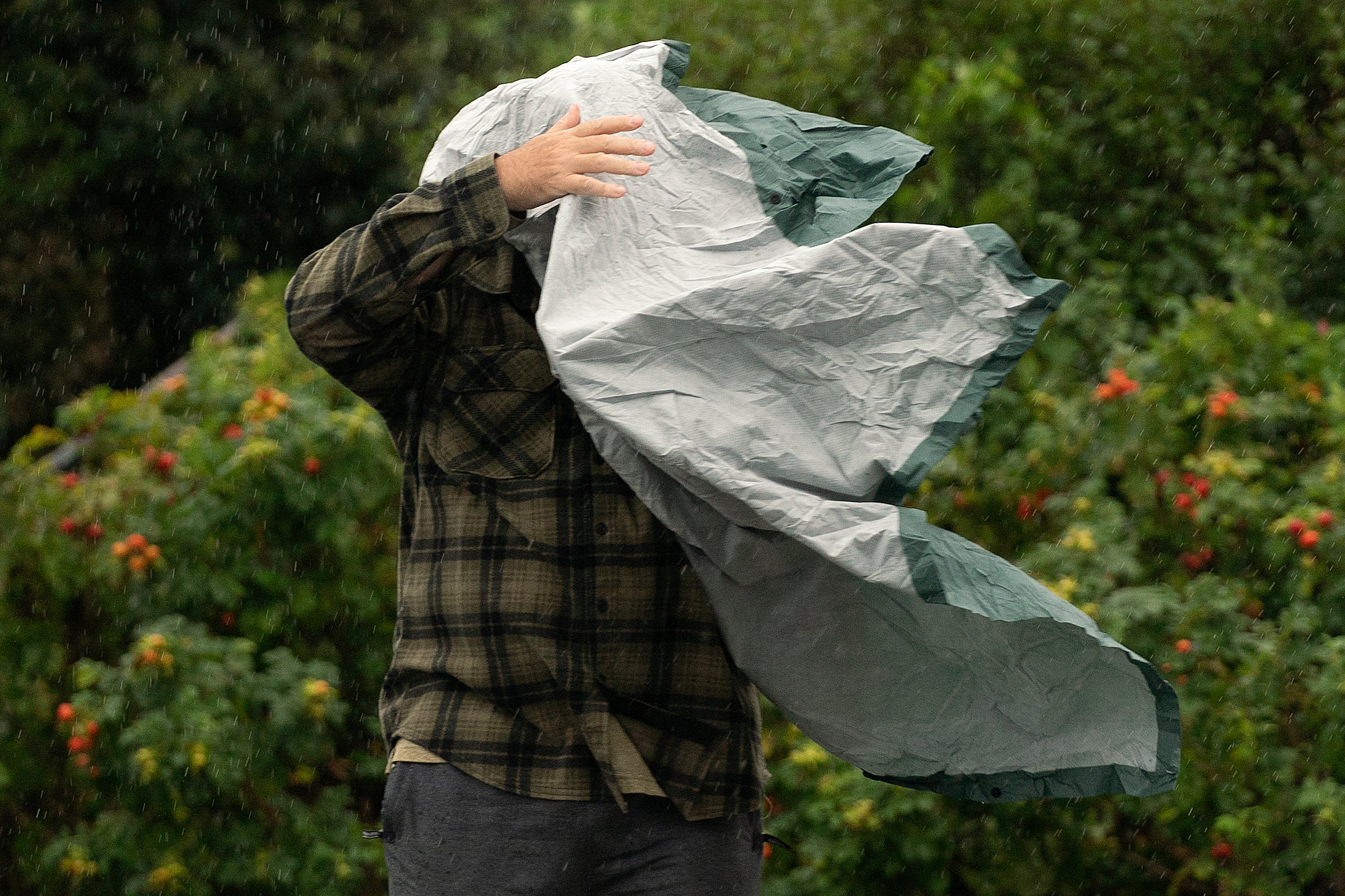 A tourist struggles with his rain poncho in strong wind in Maine. 