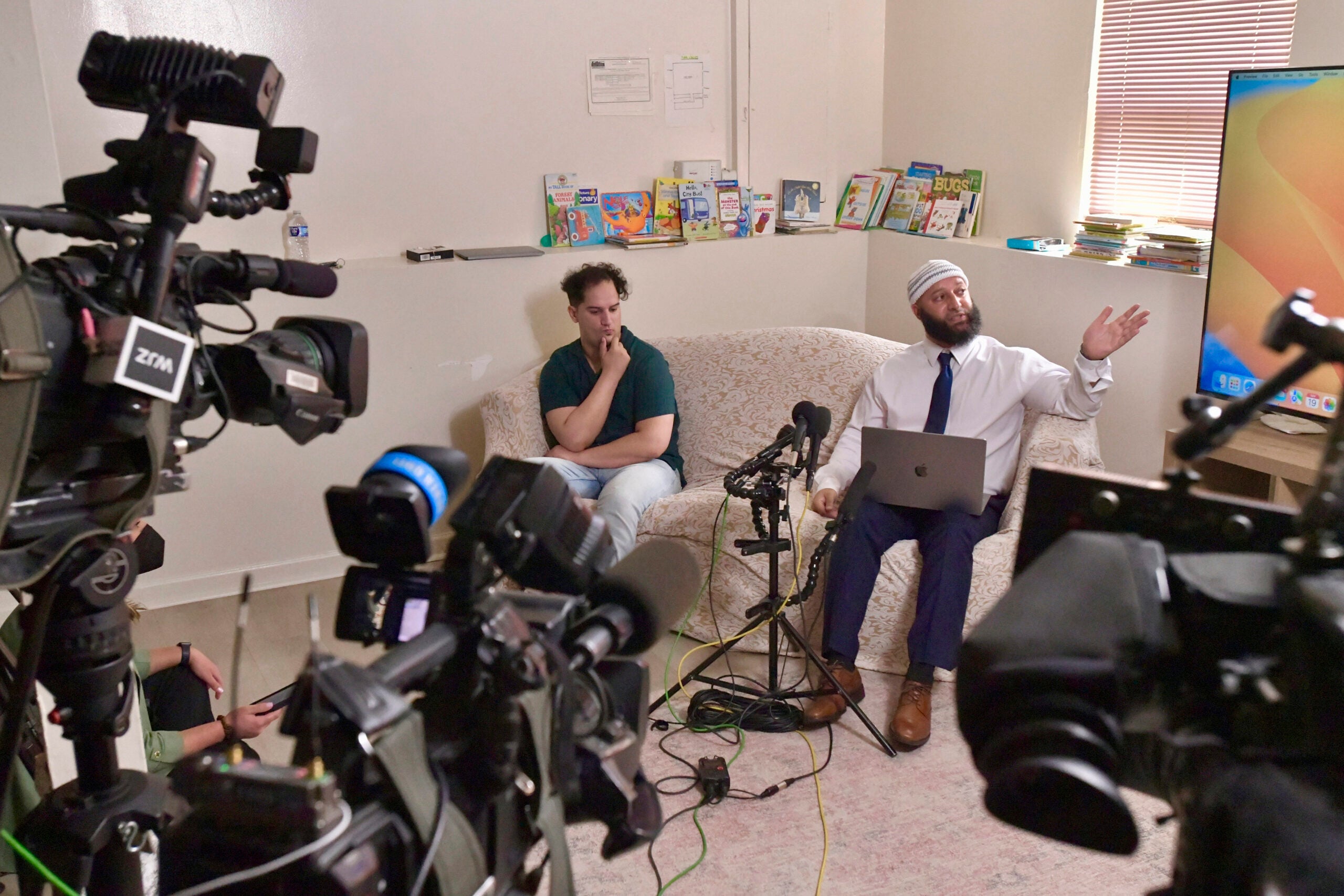 Adnan Syed presents evidence of alleged prosecutorial misconduct during a media conference at his family's home as his younger brother Yusuf Syed listens.