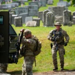 Law enforcement gather in a cemetery as they search for the escapee.