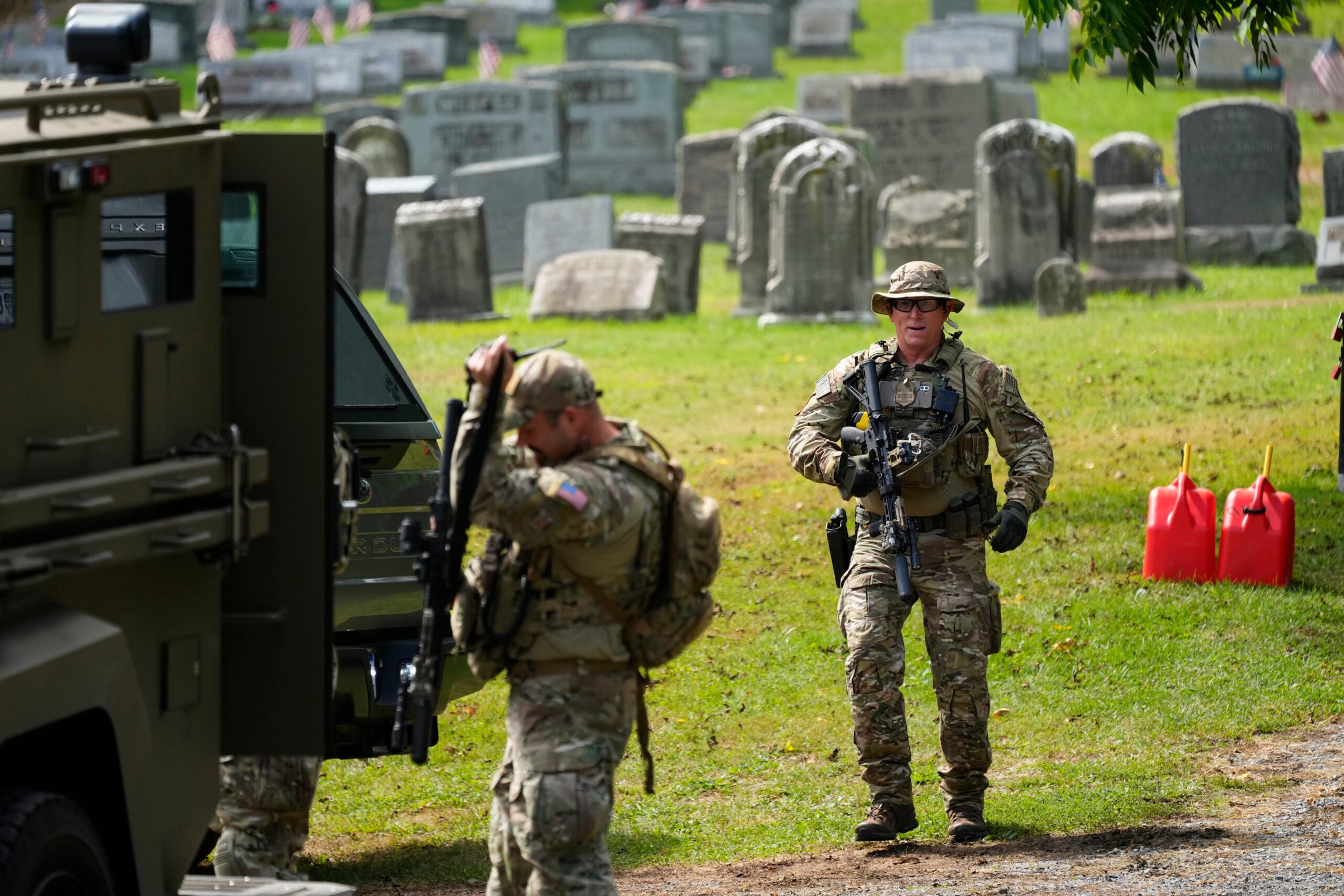 Law enforcement gather in a cemetery as they search for the escapee.