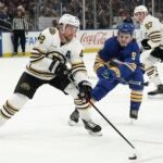 Buffalo Sabres' Zach Benson tries to get the puck from Boston Bruins' Matt Grzelcyk during the first period of an NHL hockey preseason game Tuesday, Sept. 26, 2023, in Buffalo, N.Y.