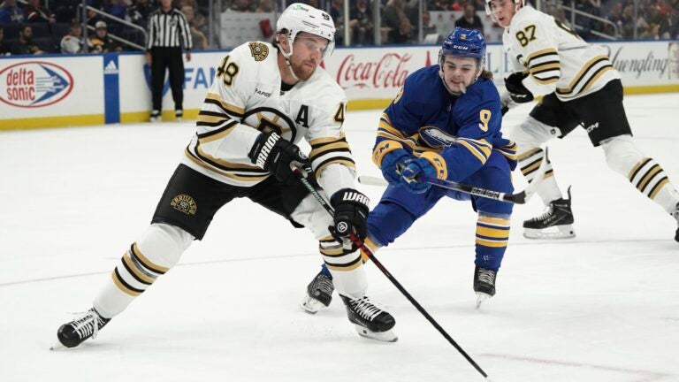 Buffalo Sabres' Zach Benson tries to get the puck from Boston Bruins' Matt Grzelcyk during the first period of an NHL hockey preseason game Tuesday, Sept. 26, 2023, in Buffalo, N.Y.