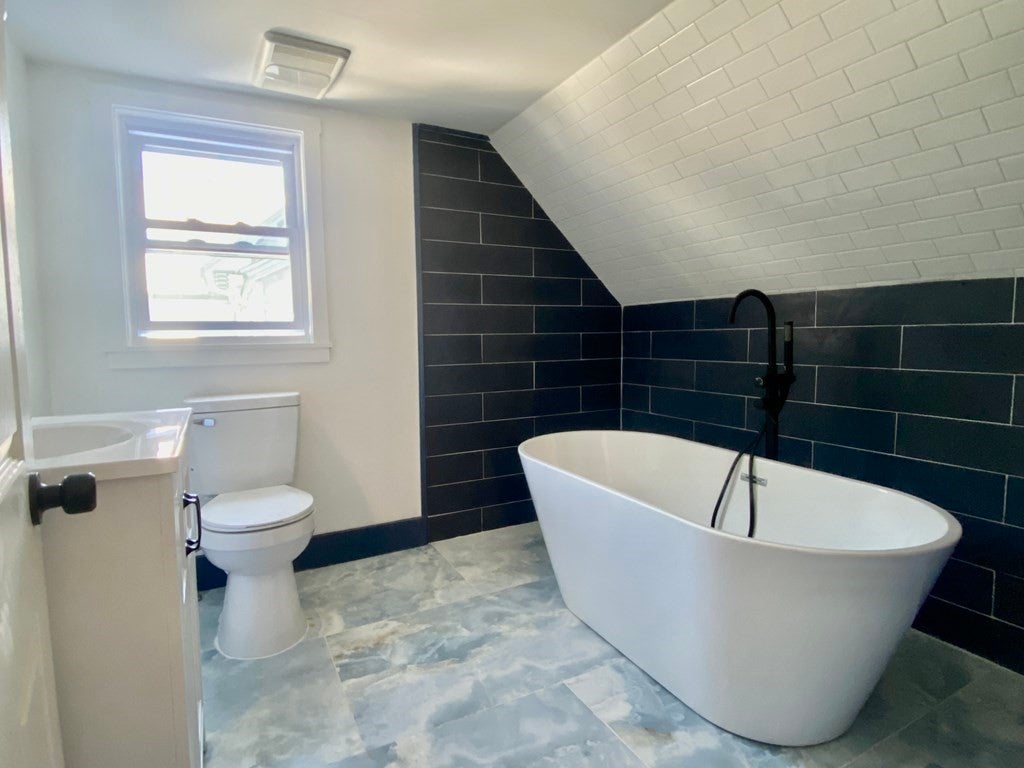 Modern bathroom with black tile, and a bath tub.