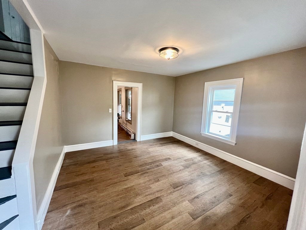 Empty living room with wood floors, and beige walls. 