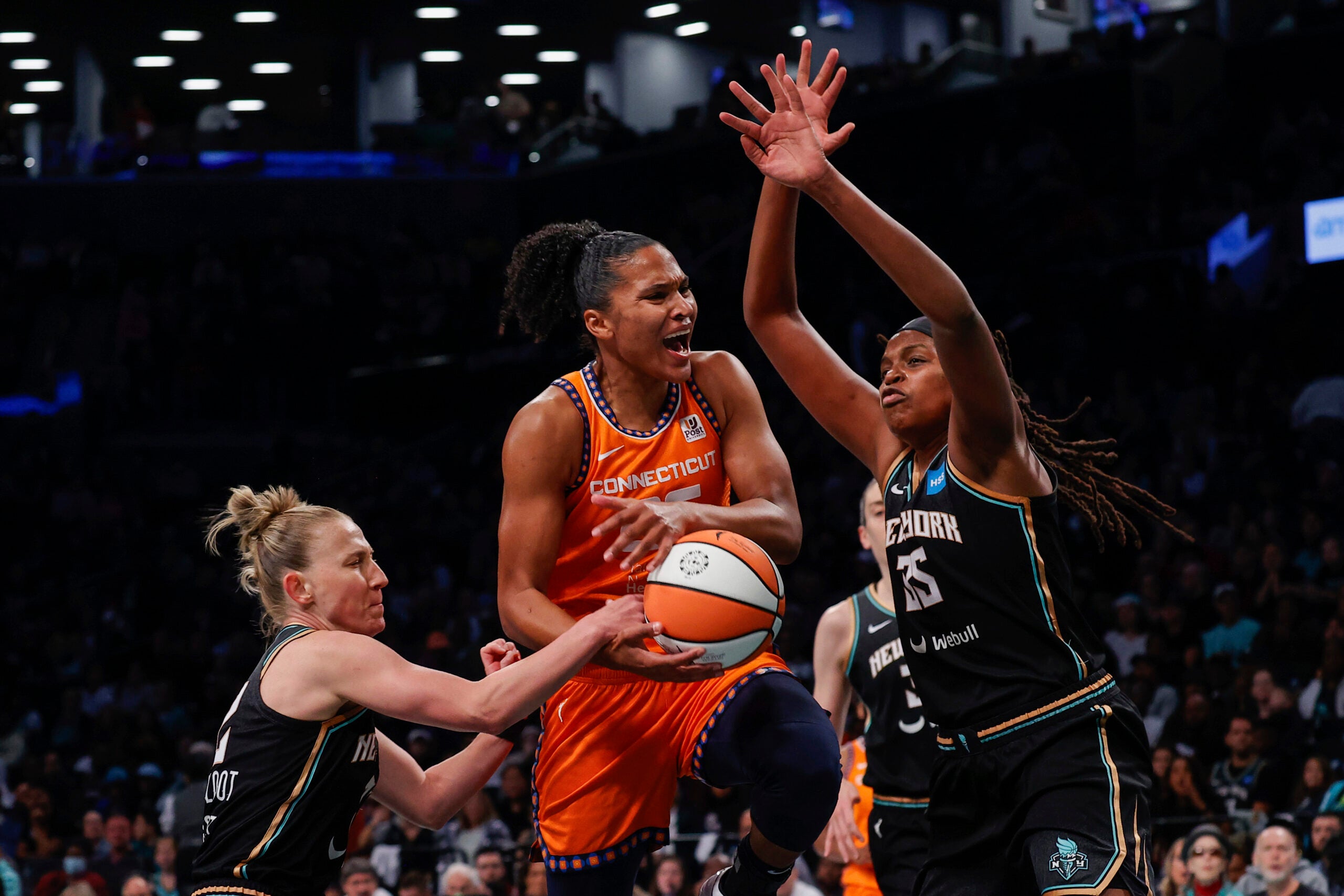 Connecticut Sun forward Alyssa Thomas, center, drives to basket against New York Liberty forward Jonquel Jones.