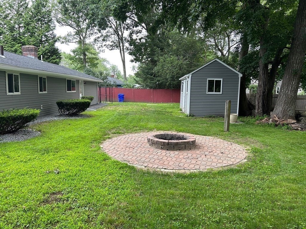 Backyard of Maynard home for sale with fire pit, and shed. 