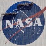 Workers on scaffolding repaint the NASA logo.