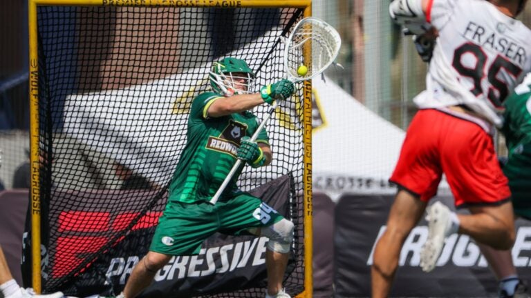 Redwoods goalie Jack Kelly, wearing a green uniform, saves a ball from going in the net.