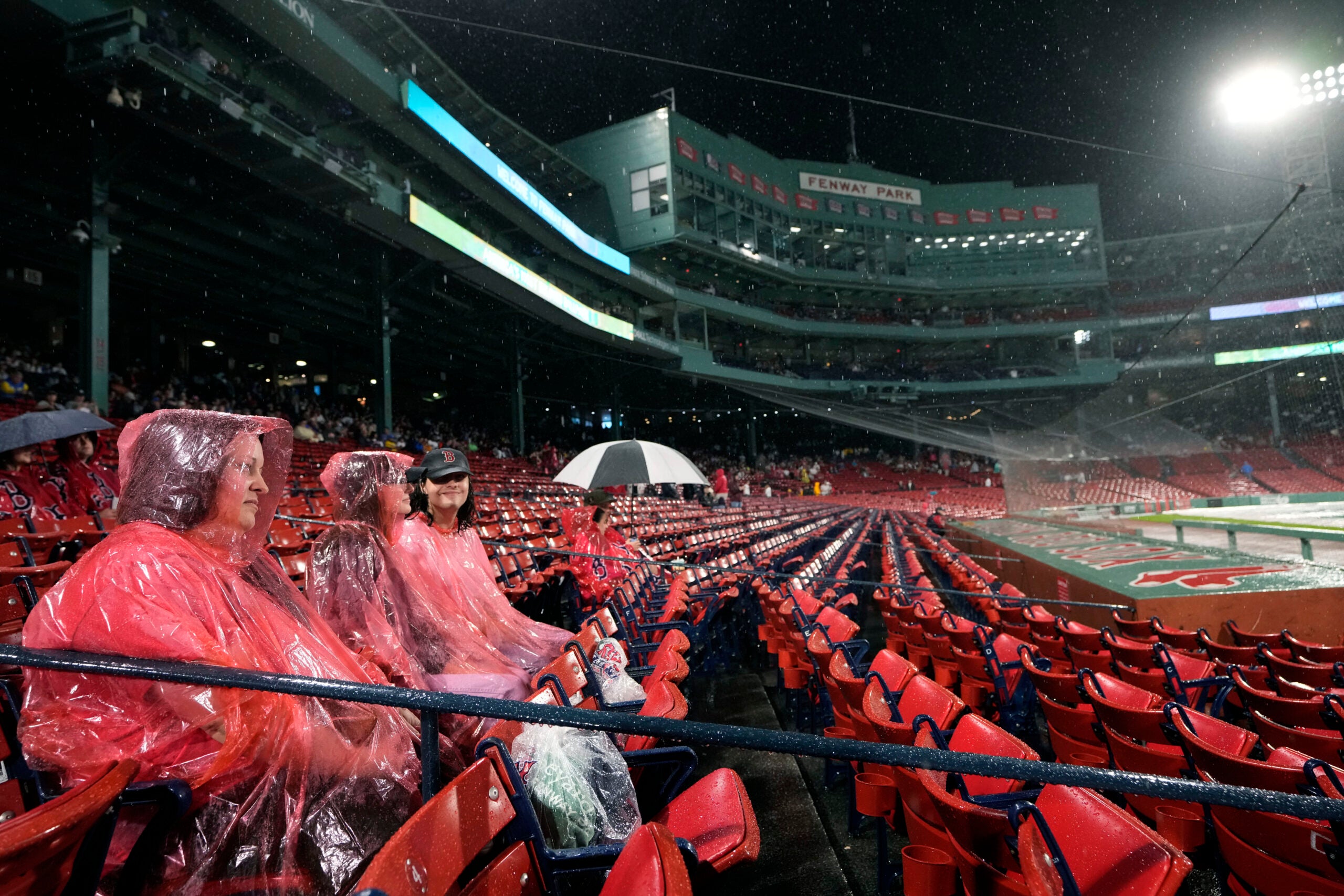 Fans wore ponchos in the stands during a rain delay at Fenway Park Wednesday.
