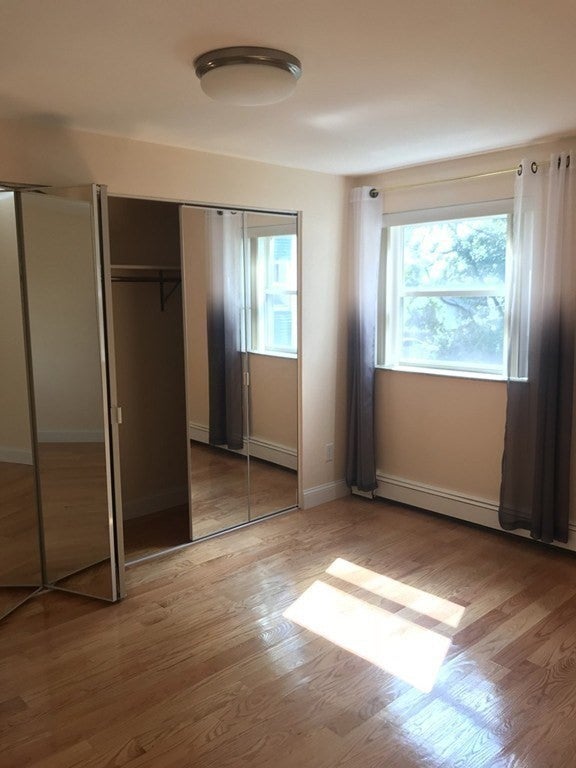 Empty bedroom with wood flooring, and mirrored closet. rent