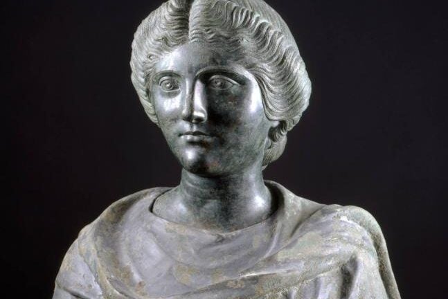 The bust of a young woman with a heavy-lidded gaze and hair carefully combed into waves.