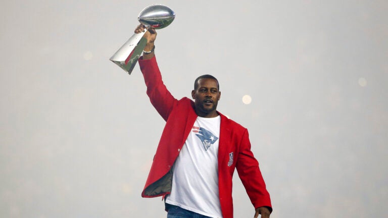 Former New England Patriots cornerback Ty Law raises one of the four Lombardi Trophies before an NFL football game between the New England Patriots and the Pittsburgh Steelers Thursday, Sept. 10, 2015, in Foxborough, Mass.