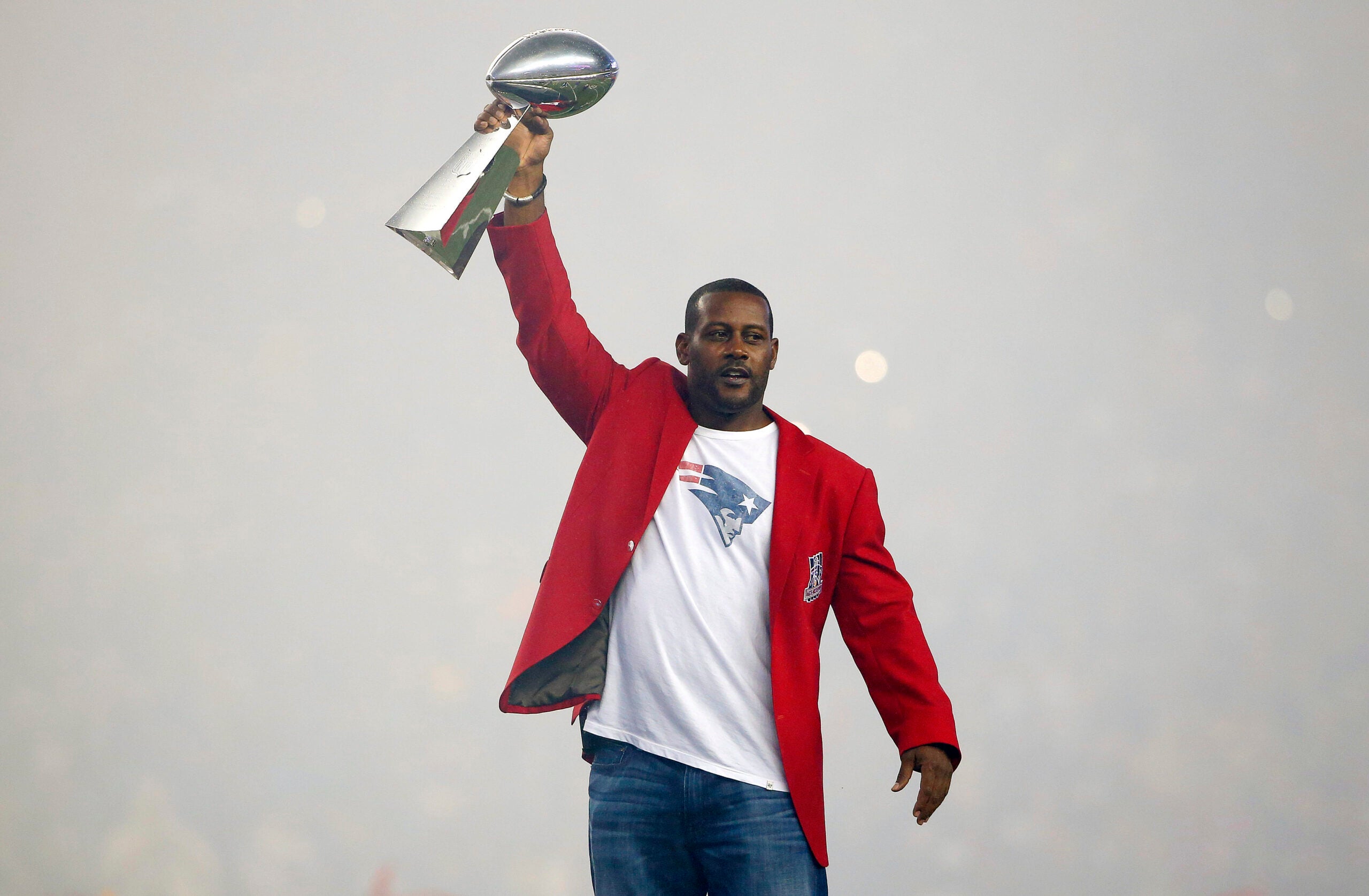 Former New England Patriots cornerback Ty Law raises one of the four Lombardi Trophies before an NFL football game between the New England Patriots and the Pittsburgh Steelers Thursday, Sept. 10, 2015, in Foxborough, Mass.
