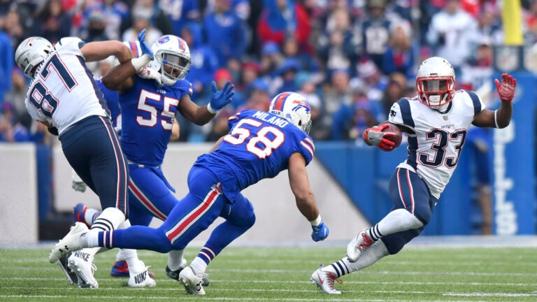 New England Patriots running back Dion Lewis (33) runs with the ball as Buffalo Bills outside linebacker Matt Milano (58) moves in for the tackle during the first half of an NFL football game, Sunday, Dec. 3, 2017, in Orchard Park, N.Y. Patriots' Rob Gronkowski (87) applies a block on Bills' Jerry Hughes (55) on the play.