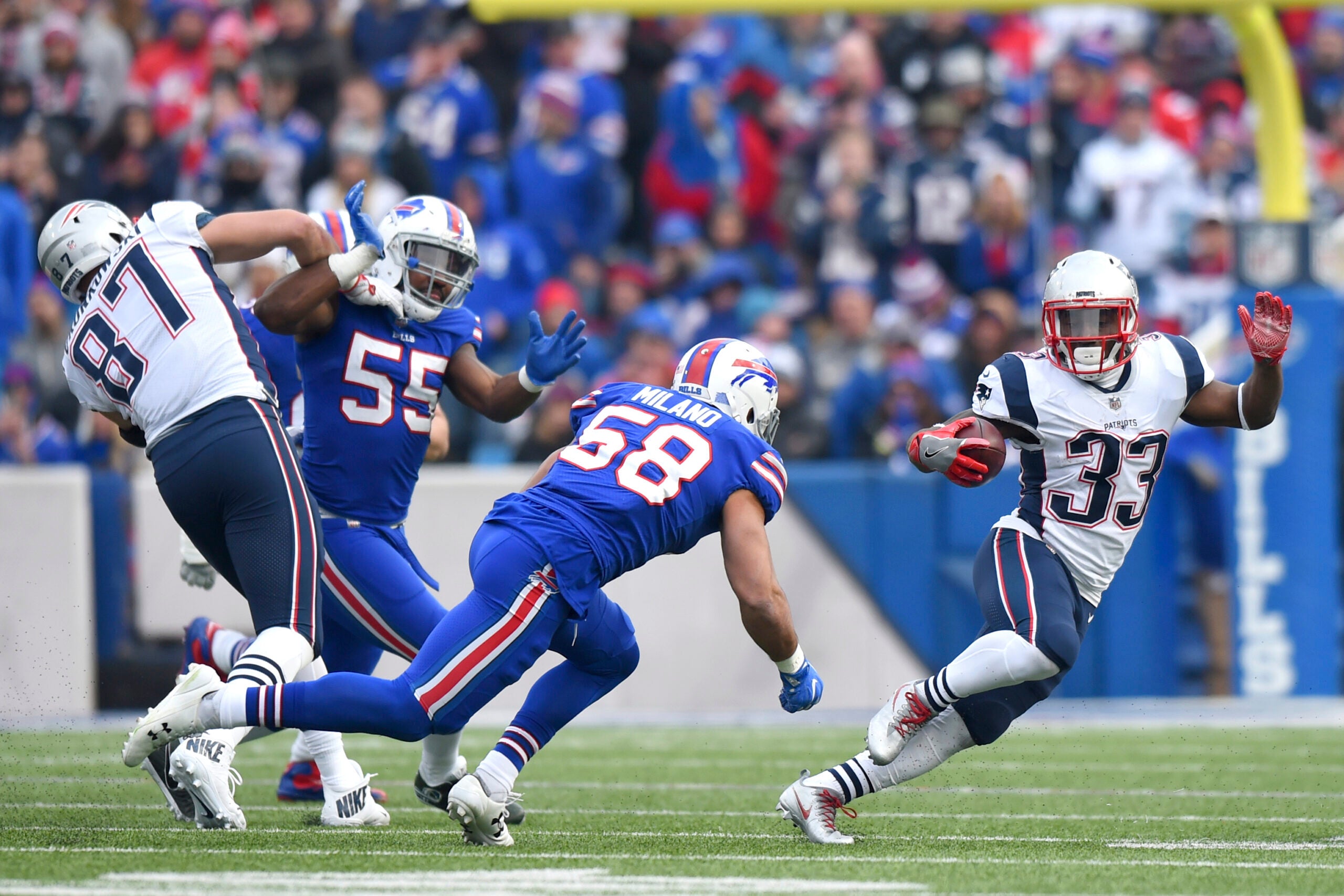 New England Patriots running back Dion Lewis (33) runs with the ball as Buffalo Bills outside linebacker Matt Milano (58) moves in for the tackle during the first half of an NFL football game, Sunday, Dec. 3, 2017, in Orchard Park, N.Y. Patriots' Rob Gronkowski (87) applies a block on Bills' Jerry Hughes (55) on the play.
