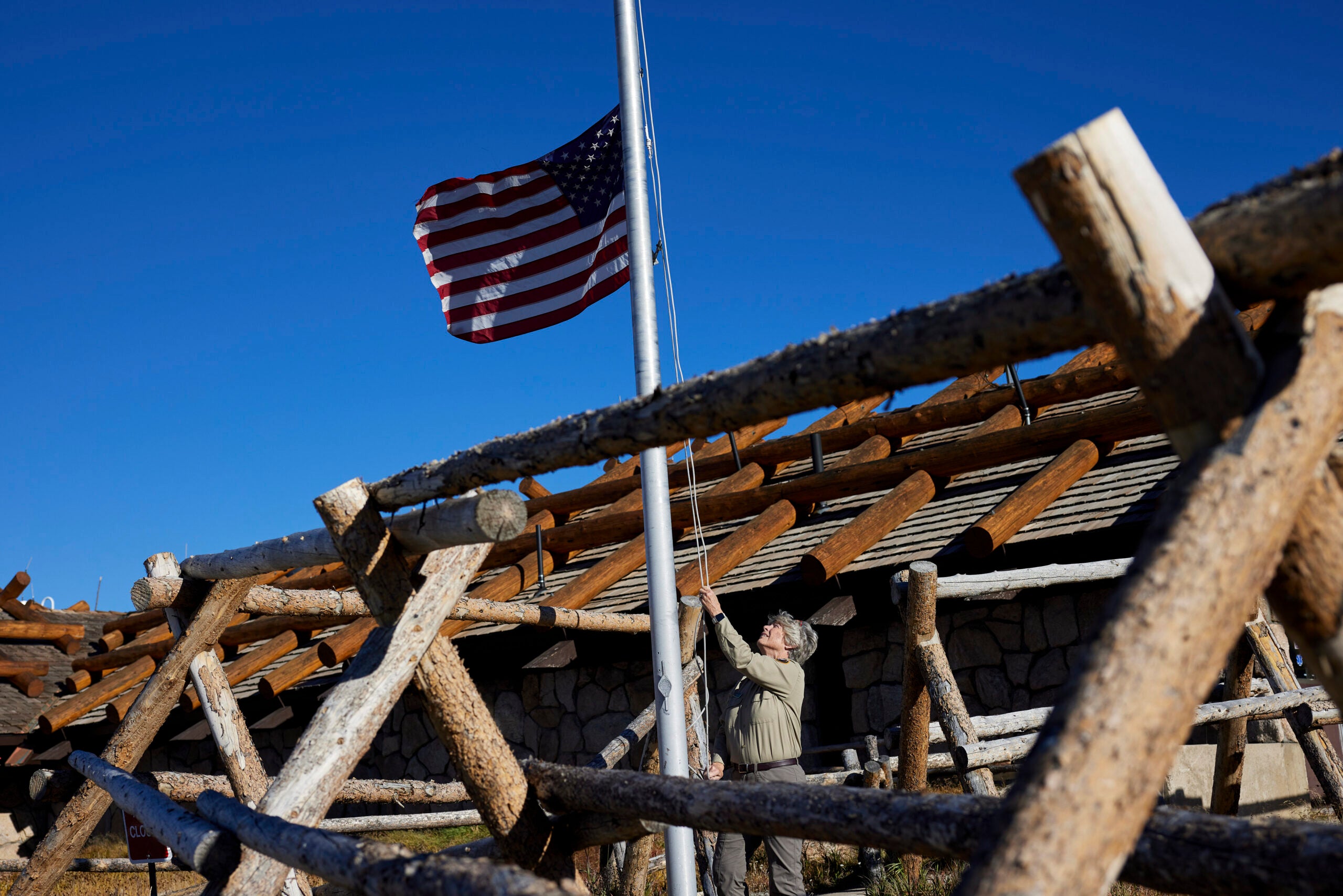 A park ranger lowers the American flag outside the Alpine Visitor Center at Rocky Mountain National Park in Colorado.