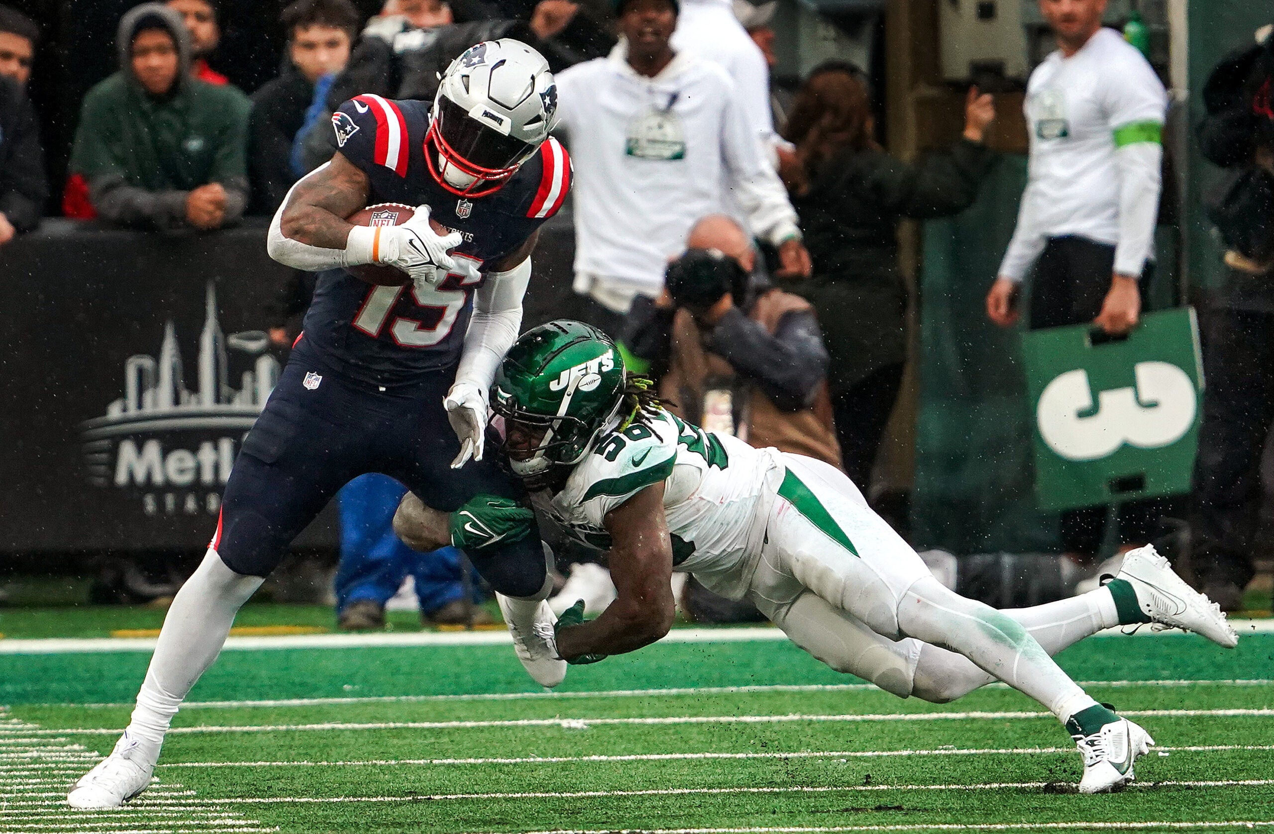 New England Patriots running back Ezekiel Elliott fights for extra yardage as he is brought down by New York Jets linebacker Quincy Williams.