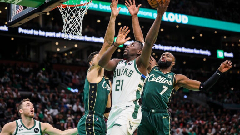 Jrue Holiday attacking the basket against multiple Celtics players.