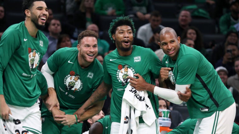 Celtics starters Jayson Tatum (left) Marcus Smart (second from right), and Al Horford (right) are on the bench late in the game as they support the reserves on the court as they finish off the game. Teammate Blake Griffin (second from left) who did not play (despite the crowd chanting for him to be put in) joined them. The Boston Celtics hosted the Detroit Pistons in a regular season NBA basketball game at the TD Garden.