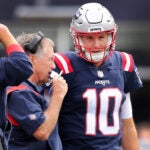 Patriots quarterback Mac Jones (right) listens to head coach Bill Belichick (left) on the sidelines. Joe Judge is at far left. The New England Patriots hosted the Baltimore Ravens in a regular season NFL football game at Gillette Stadium.
