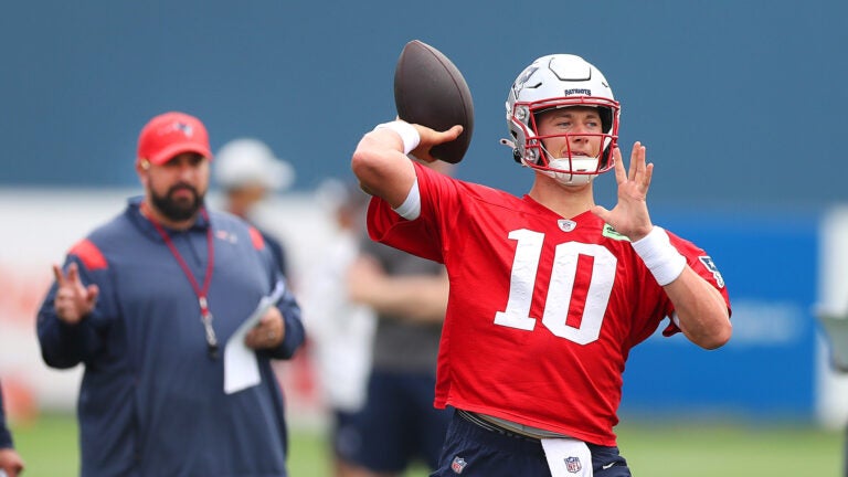 Matt Patricia(left) keeps an eye on qb Mac Jones firing a pass as the New England Patriots held their 2nd day of training camp on the practice fields behind Gillette Stadium on Thursday morning.