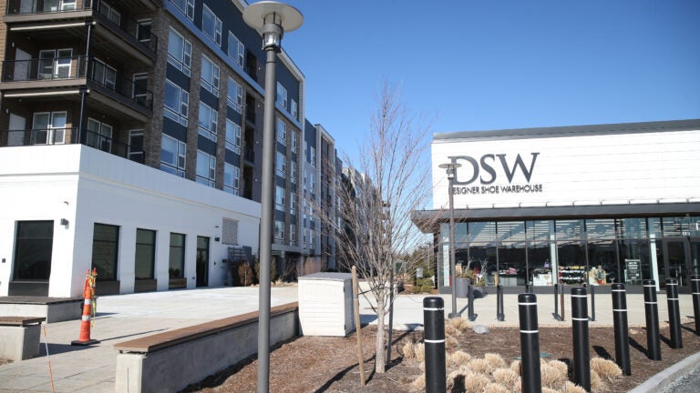 a view of a four-story apartment building next to a DSW shoe store.