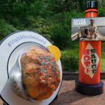 An image of a Rhode Island "stuffie" installation, a 200-pound styrofoam version of the baked clam, on a plate and next to an 8-foot bottle of hot sauce.