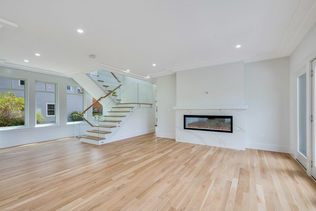 Unfurnished living room with fireplace, and stairs in Wellesley home. 