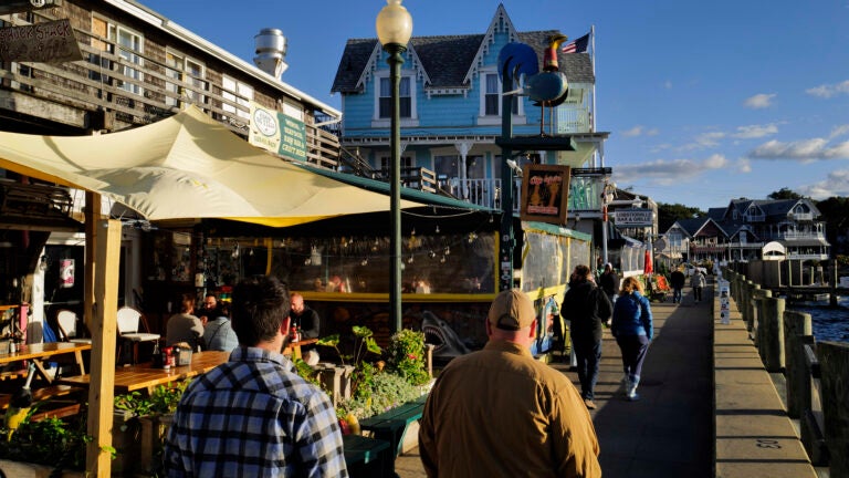 Several people walk past two businesses in Dockside Marina in Oak Bluffs, a beach town on Martha's Vineyard.