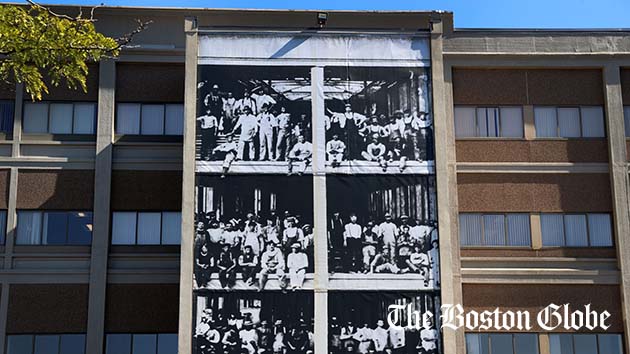 A banner hangs on the facade of a photograph taken when the factory was under construction.