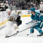 Charlie Coyle #13 of the Boston Bruins and Kyle Burroughs #4 of the San Jose Sharks skate for control of the puck during the first period at SAP Center on October 19, 2023 in San Jose, California.