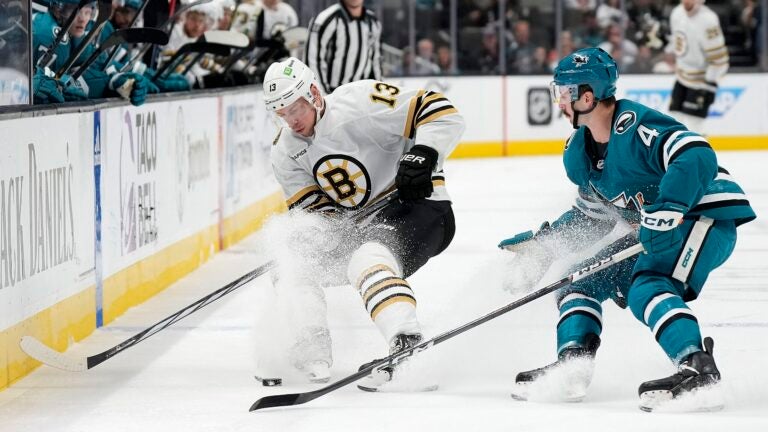 Charlie Coyle #13 of the Boston Bruins and Kyle Burroughs #4 of the San Jose Sharks skate for control of the puck during the first period at SAP Center on October 19, 2023 in San Jose, California.