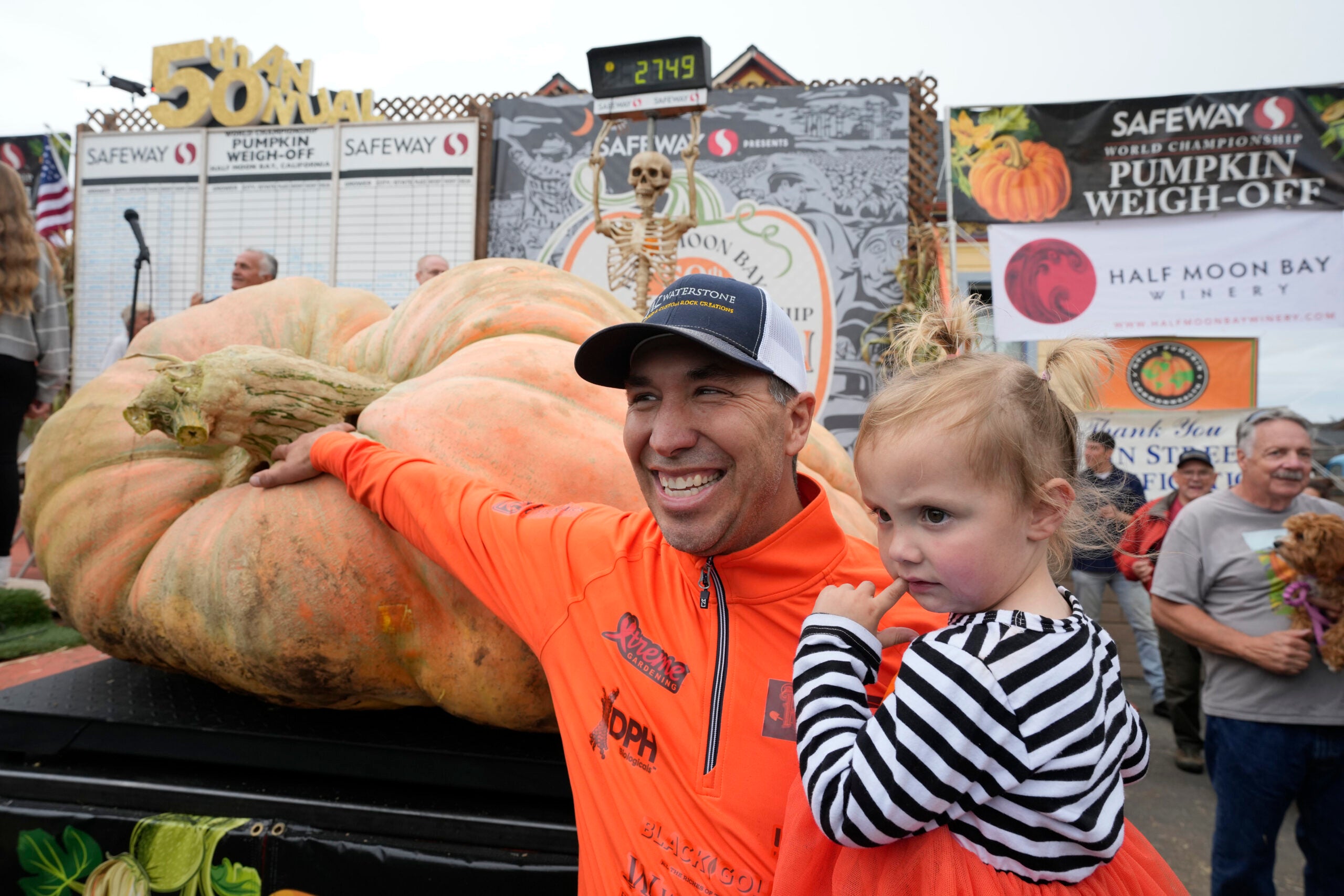 Travis Gienger of Anoka, Minn., holds his two-year-old daughter Lily and poses by his pumpkin called "Michael Jordan" after winning the Safeway 50th annual World Championship Pumpkin Weigh-Off in Half Moon Bay, Calif.