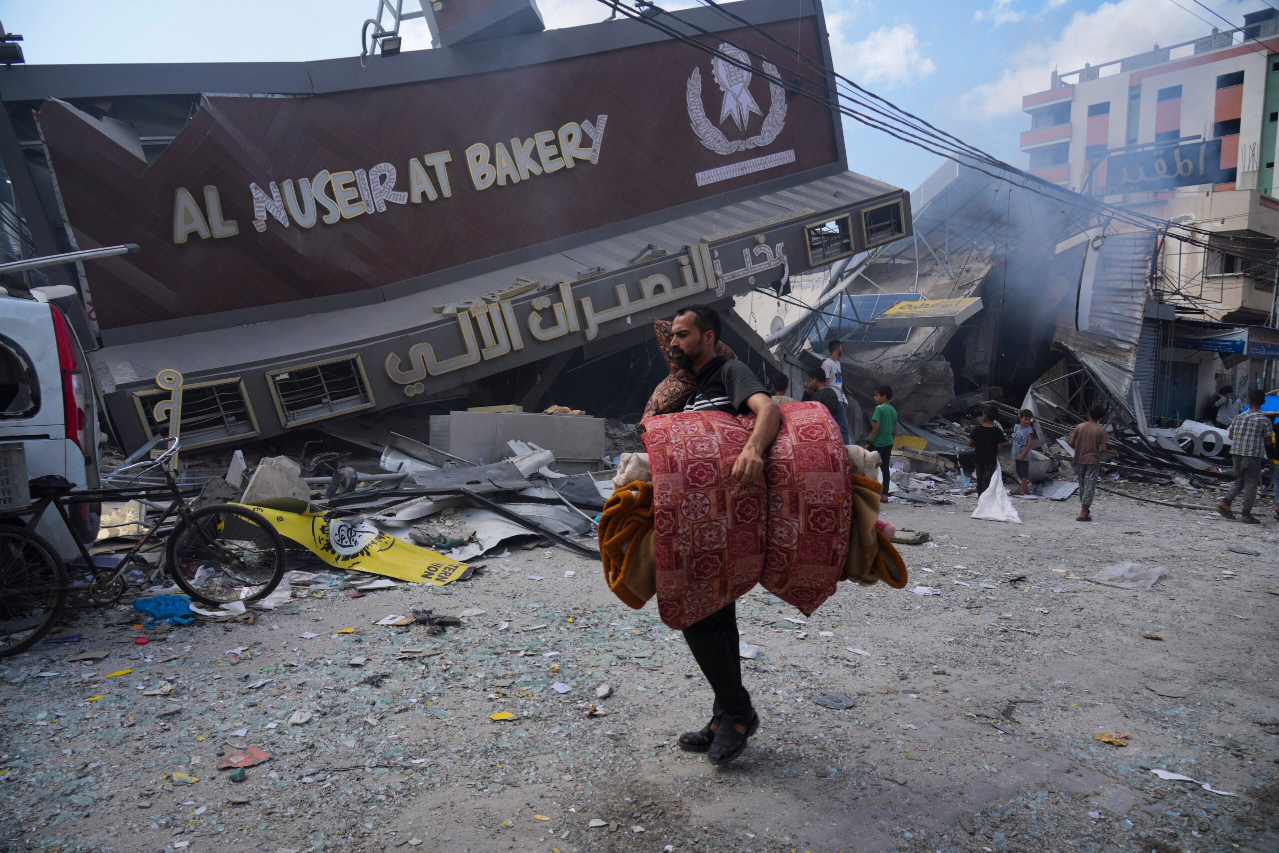 Palestinians walk by the destroyed building of Al Nuseirat Bakery. 